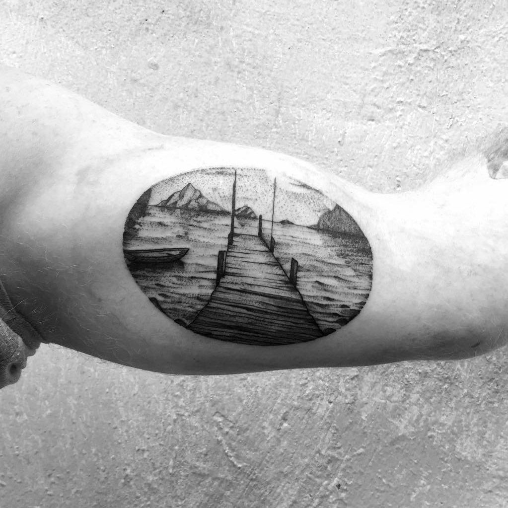 Ponton et montagnes en dotwork dans un cercle, sur le bras — Nik Costaz